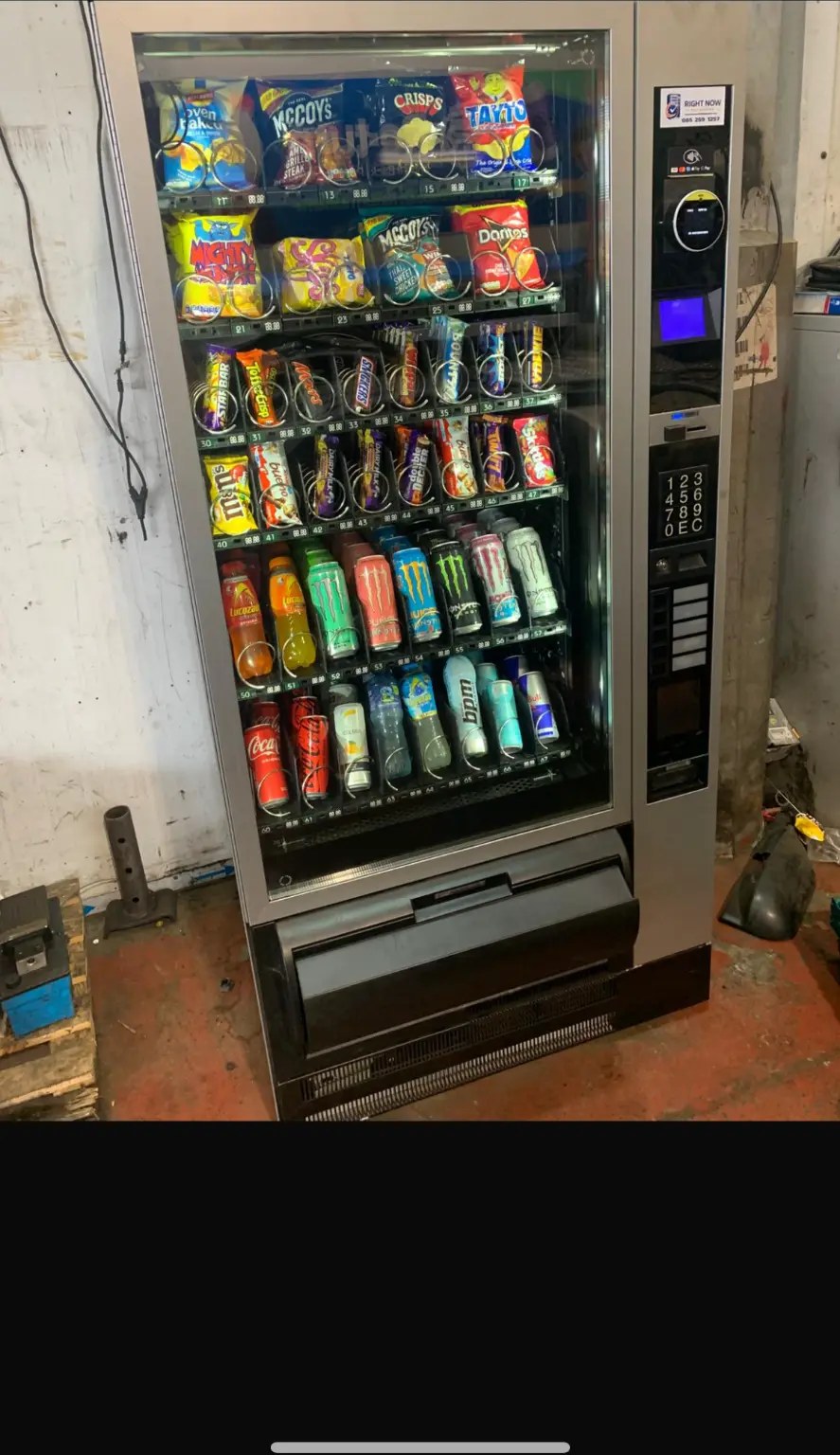 Vending machine stocked with snacks and energy drinks on a warehouse floor