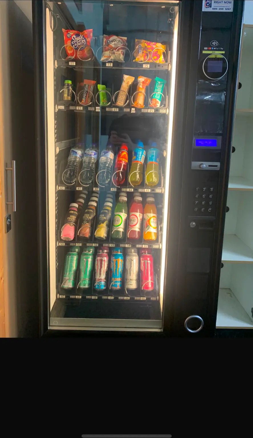 Vending machine stocked with protein shakes, water and energy drinks on a gym floor